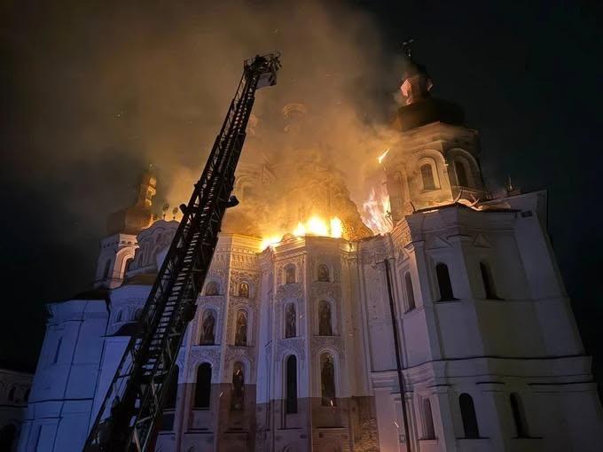 Historic Orthodox cathedral engulfed in flames after a Russian strike, with a fire ladder raised against it